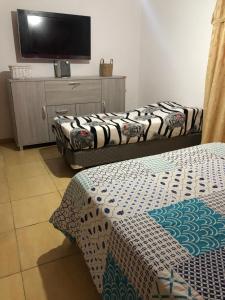 a room with two beds and a flat screen tv at J & S Casa de Alquiler Temporario in Santiago del Estero