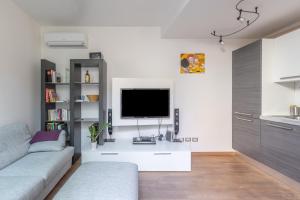 Chic & Modern apartment with terrace في بولونيا: غرفة معيشة مع أريكة وتلفزيون على الحائط