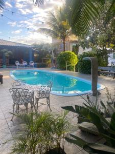 a pool with two chairs and a table in front of it at Pousada Cantim de BH in Venda Nova