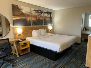 Days Inn & Suites Mobile في تيلمانز كورنر: غرفة في الفندق مع سرير ومكتب وسيكس السرير