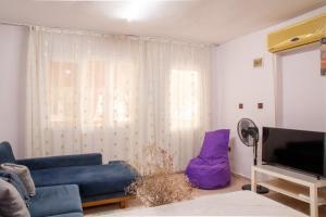 uma sala de estar com um sofá azul e uma televisão em Flat with Large Balcony in Izmir em Esmirna