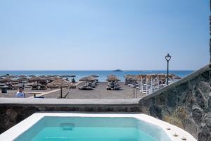 a swimming pool next to a beach with umbrellas at Sand Gem - Beach Apartments in Perivolos