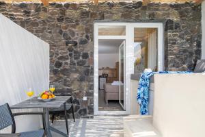 a room with a table and a stone wall at Sand Gem - Beach Apartments in Perivolos