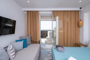 1 dormitorio con cama, sofá y ventana en Sand Gem - Beach Apartments, en Perivolos