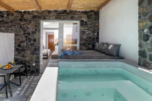 a pool in a room with a stone wall at Sand Gem - Beach Apartments in Perivolos