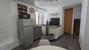 a small kitchen with a refrigerator and a microwave at L'Entracte - Appart Hôtel - Hypercentre in La Ferté-Alais