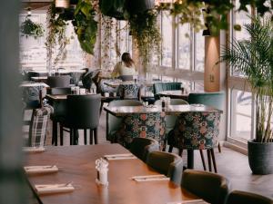 カーディフにあるRooms at The Deck, Penarthのテーブルと椅子が並ぶレストランで、女性が背景に座っているレストランです。