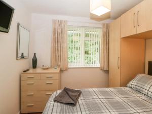 a bedroom with a bed and a dresser and a window at Sycamores in Liskeard