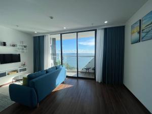 a living room with a blue couch and a view of the ocean at 2S Ha Long Homestay in Ha Long