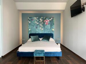 a bedroom with a blue bed with a painting on the wall at Le Finestre Sul Lago in Cesenatico