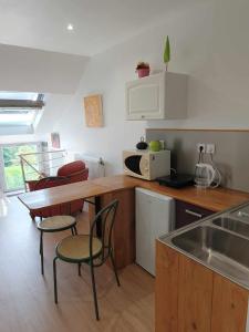 eine Küche mit einem Tisch, Stühlen und einer Arbeitsplatte in der Unterkunft Le Duplex - La Capelette de Dany.D in Étroeungt