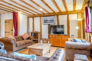 uma sala de estar com mobiliário de couro e uma televisão de ecrã plano em Elms Barn em Saint James