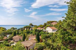 Saint-Peïre-sur-MerBeau T2 avec terrasse Vue mer的一座树木和海洋的小山上的房子