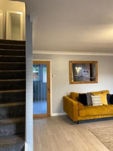 a living room with a yellow couch and stairs at Comfy Darlington Home in Darlington