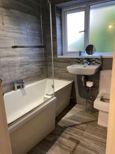 a bathroom with a tub and a sink and a toilet at Comfy Darlington Home in Darlington
