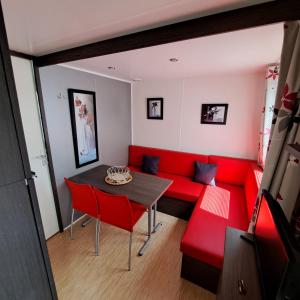 sala de estar con sofá rojo y mesa en Mobile home à louer Les Sables d'Olonne - Vendée, en La Pironnière