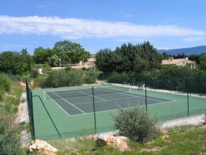 una pista de tenis en una colina junto a una casa en La Bastide de la Peyrolière avec piscine et tennis face au Luberon, en Apt