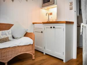 a living room with a sink and a chair at Helens Shepherds Hut in Enford