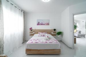 a white bedroom with a bed with pink sheets at Casa Higuera in Nerja