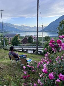 a man sitting in a chair in a yard with flowers at Hostel Bear Hug in Plav