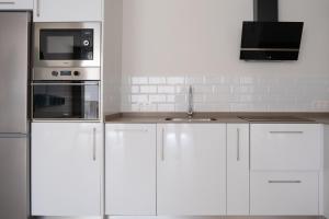 a kitchen with white cabinets and a sink and a microwave at Victoria's Home modern and cosy 2 bedroom apartment in Málaga