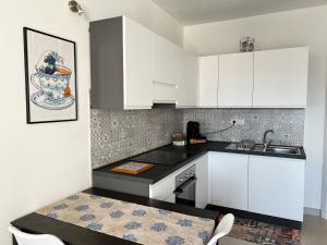 eine Küche mit weißen Schränken, einer Spüle und einem Tisch in der Unterkunft Sunnyside Apartment in Torre Grande