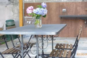a table with a vase of flowers and two chairs at villa amarena, centralissima giardino e parcheggio in Angera