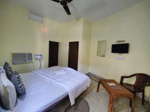 a bedroom with a bed and a table and a tv at Hotel Surya Greens in Puri