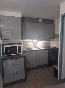 a kitchen with a microwave on top of a counter at Logement plage in Saint-Cyprien