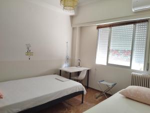a bedroom with two beds and a desk and a window at Vacations in Patra in Patra