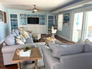 Una sala de estar con dos sofás y un televisor. en Manatee Manor Beachfront Retreat, en Daytona Beach