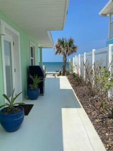 un porche de una casa con una silla y la playa en Manatee Manor Beachfront Retreat, en Daytona Beach