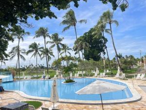 una piscina con sombrilla y palmeras en Casa Paradise Fiore, en Paripueira