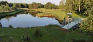 a bridge over a pond with a house on it at Owczarkowa Zagroda in Wąsosz
