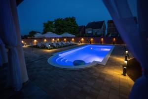 a swimming pool at night with tables and chairs at Villa Biser Dunava in Vukovar