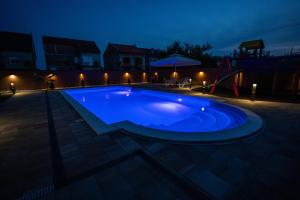 a large blue swimming pool at night at Villa Biser Dunava in Vukovar