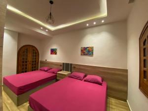 duas camas num quarto com lençóis cor-de-rosa em Marina 5 em El Alamein