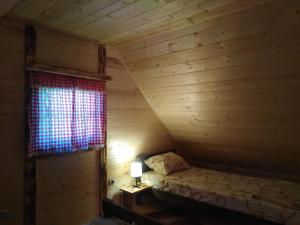 a bed in a wooden room with a window at Koliba kod Vukašina in Kremna