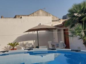 a swimming pool with an umbrella and chairs at Dimora allo stagnone in Marsala