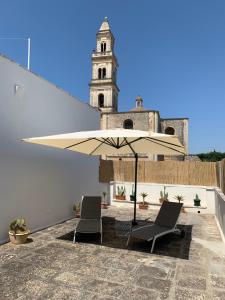 un patio con due sedie e un ombrellone e un edificio di CONTINOWINES a Lequile