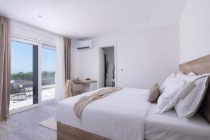 a white bedroom with a large bed and a balcony at Stunning Wind Rose with 50m2 heated pool, Sauna, Gym in Trogir