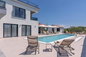 a villa with a swimming pool and lounge chairs at Stunning Wind Rose with 50m2 heated pool, Sauna, Gym in Trogir