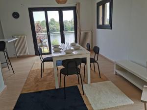 une salle à manger avec une table et des chaises blanches dans l'établissement La Rive du Doubs - 2 chambres - 5 Pers - 56, Chemin du Canal Du Rhône au Rhin, à Dole