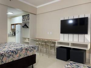 a bedroom with a bed and a flat screen tv at Spazzio Di Roma - Apartamentos para Temporada in Caldas Novas