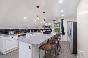 a kitchen with white cabinets and a island with bar stools at 5 Star Penthouse King Deck AC Train 