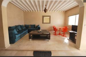 een woonkamer met een blauwe bank en een tafel bij Charment logement avec une terrasse privée. in Agadir