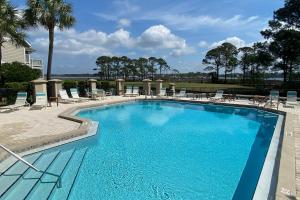 a large swimming pool with chairs and a beach at Waterfront Haven Retreat in Destin