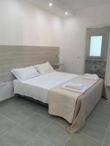 a bedroom with a bed with white sheets and a window at Campeggio 2 Mari in Ovile la Marinella