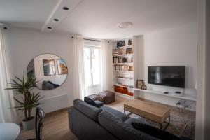 sala de estar con sofá y TV en Appartement avec jardin en Pacy-sur-Eure