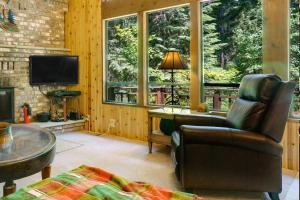 a living room with a chair and a tv and windows at Yakima River Cabin in Cle Elum
